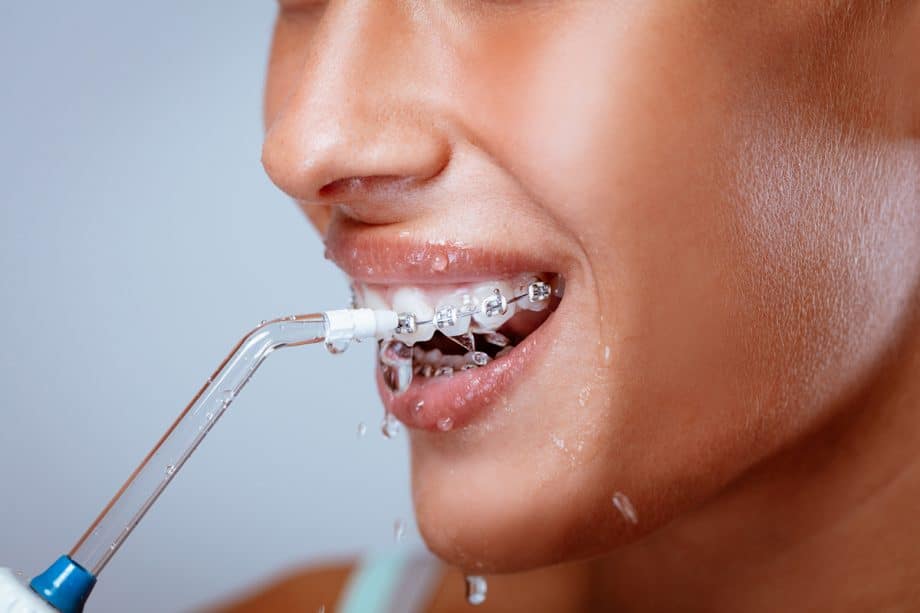 woman using Waterpik to floss with braces