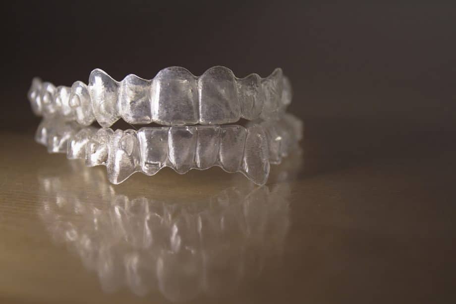 Pair of Invisalign clear aligner trays sitting on reflective surface